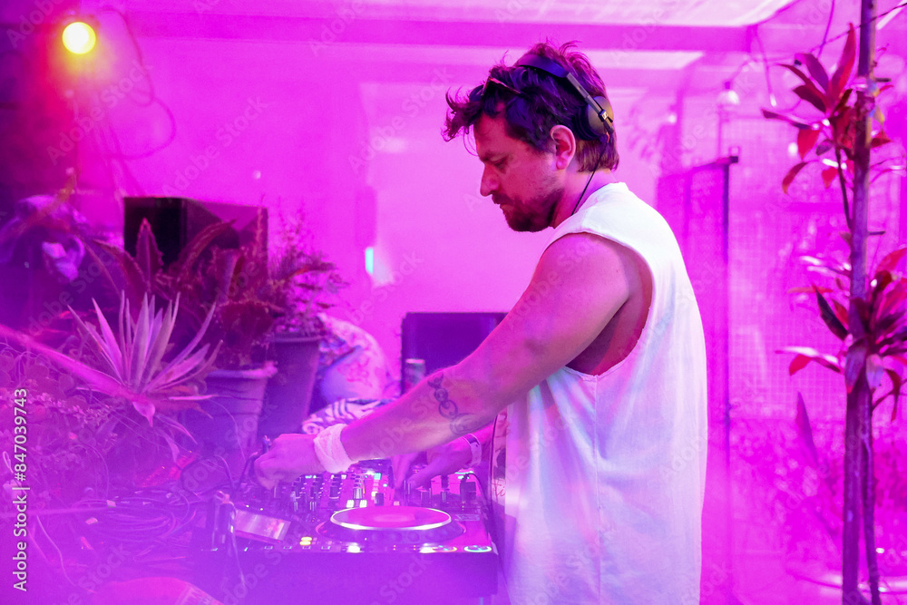 Man playing and making electronic music at party surrounded by plants
