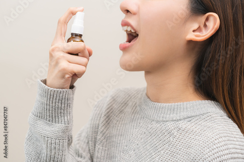 Foto Health care treatment sore throat concept, sick pain asian young woman have cough symptom holding medicine bottle, using spray in mouth to protect disease from bacteria, illness from virus infection