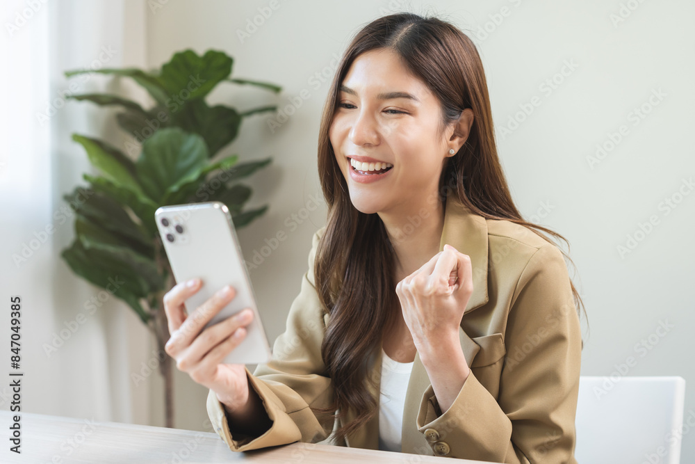 Happy cheerful asian young woman celebrate online looking at smart phone on mobile app screen, receive good news, enjoying with great offer from social, hands expression, gesture successful at office. Happy cheerful asian young woman celebrate online looking at smart phone on mobile app screen, receive good news, enjoying with great offer from social, hands expression, gesture successful at office.