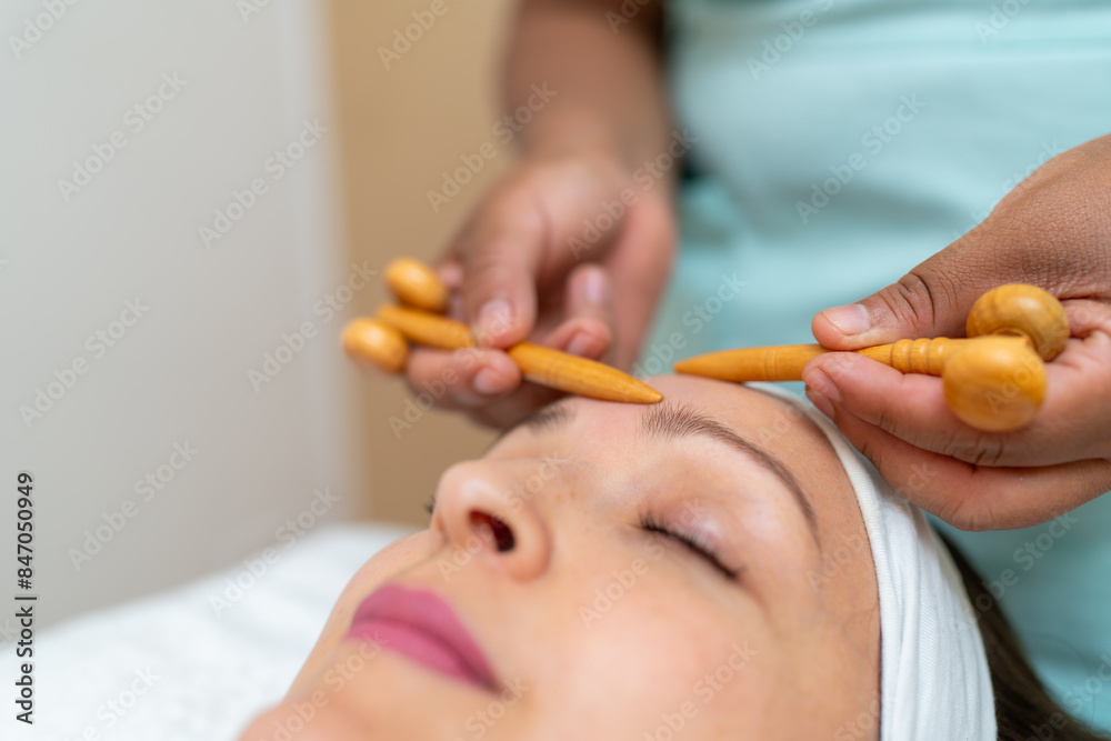 Forehead massage using wooden rollers in spa