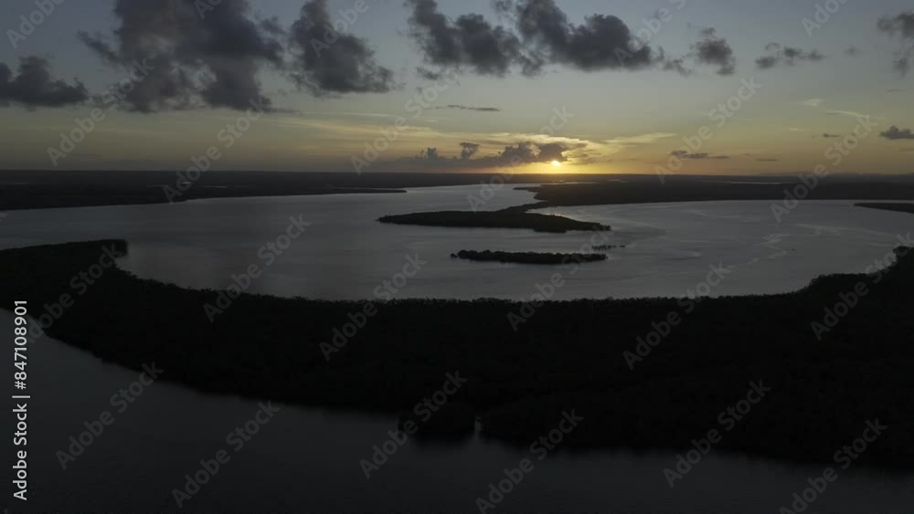 Drone lowers from high over river with sunset in the distance Drone lowers from high over river with sunset in the distance