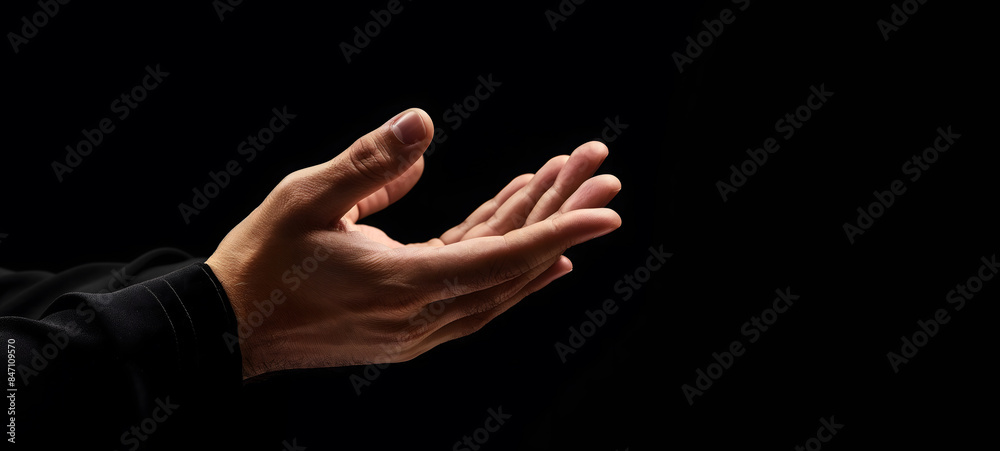 Fototapeta premium Praying Hands with White Embroidered Robe Against Dark Background