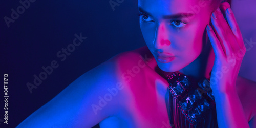 Canvas Print A woman is bathed in blue and pink neon lighting at night