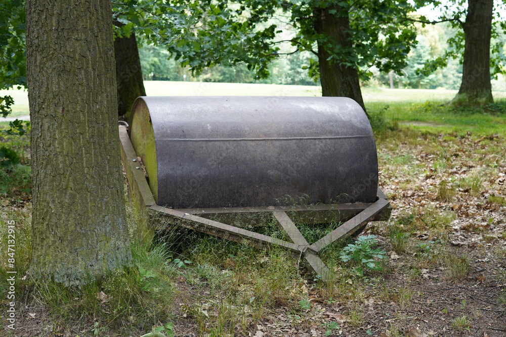A large and old iron cylinder behind a tractor. A large and old iron cylinder behind a tractor.