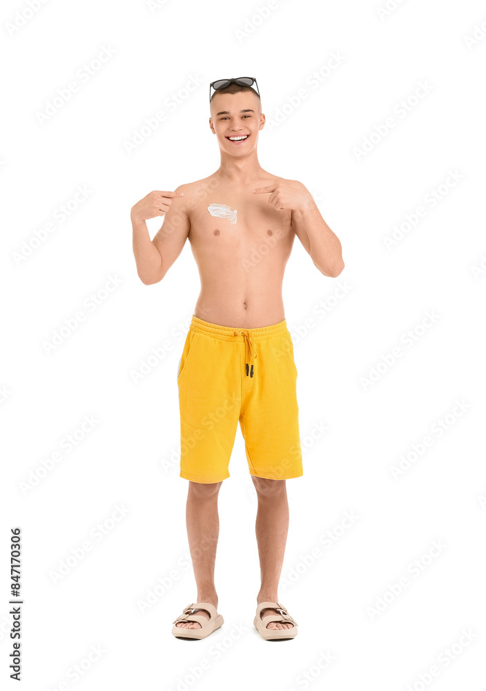 Happy young man in sunglasses pointing at sunscreen cream on his body against white background Happy young man in sunglasses pointing at sunscreen cream on his body against white background