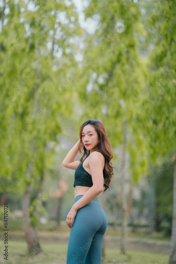Asian woman trainer is engaged in fitness in public park. Sporty woman does exercises in the open air. Healthy lifestyle, sports outdoor activities in park Asian woman trainer is engaged in fitness in public park. Sporty woman does exercises in the open air. Healthy lifestyle, sports outdoor activities in park