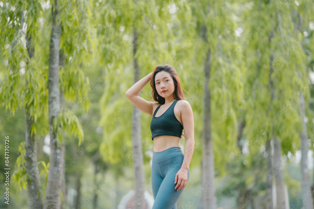 Asian woman trainer is engaged in fitness in public park. Sporty woman does exercises in the open air. Healthy lifestyle, sports outdoor activities in park Asian woman trainer is engaged in fitness in public park. Sporty woman does exercises in the open air. Healthy lifestyle, sports outdoor activities in park