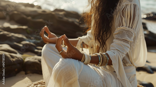 Close-up of the hands of a girl dressed in boho style. Prayer or meditation on the ocean shore.