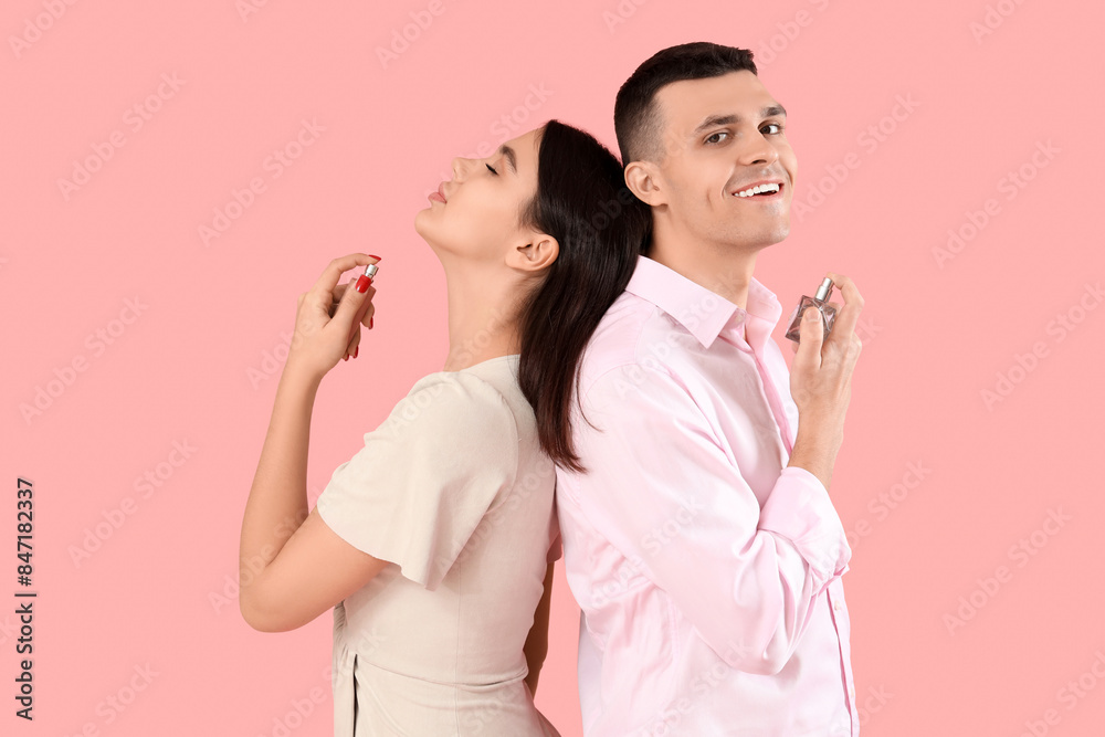Young couple applying perfume on pink background Young couple applying perfume on pink background