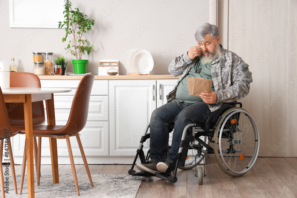 Portrait of sad senior veteran in wheelchair reading letter and wiping eyes at home Portrait of sad senior veteran in wheelchair reading letter and wiping eyes at home