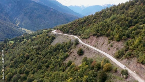 Aerial view of the road among the mountains. The car drives among beautiful and high mountains. All around are mountainous expanses, trees, nature. 4k drone video. Sunset over a city skyline.