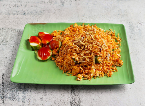 nasi goreng ikan bilis with fried onion and cucumber served in dish isolated on grey background side view of singapore food photo