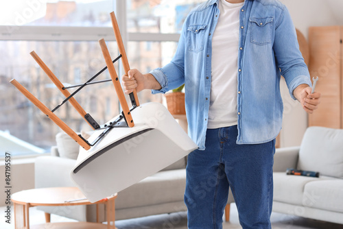 Man assembling modern white chair with wooden legs, home improvement and furn...