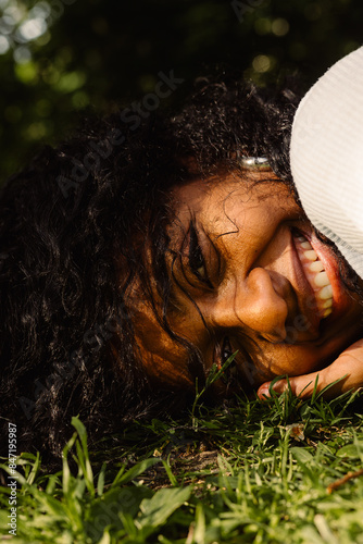 Portrait of an Afro-European girl, smiling, lying on the grrass photo