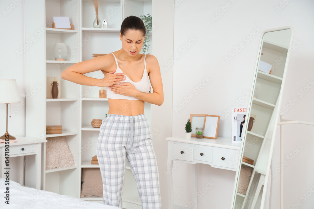 Beautiful woman checking her breast in bedroom. Cancer awareness concept Beautiful woman checking her breast in bedroom. Cancer awareness concept