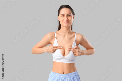 Young woman checking her breast on light background. Cancer awareness concept © Pixel-Shot