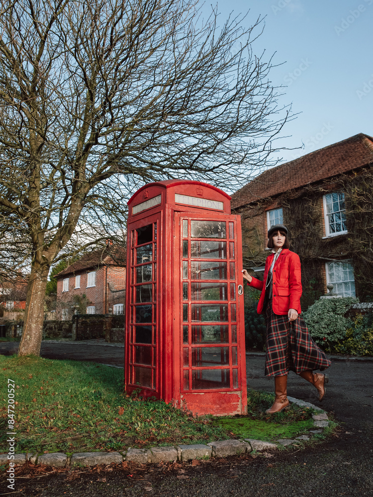 A travel scene featuring a woman posing near a red telephone booth A travel scene featuring a woman posing near a red telephone booth