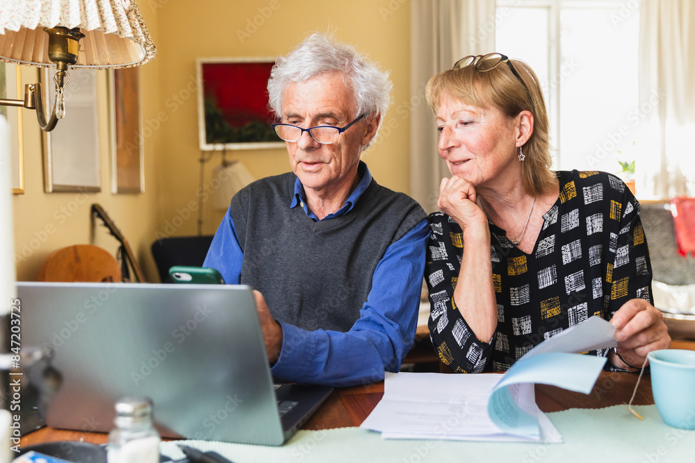 Senior citizen sitting at home paying family bills together Senior citizen sitting at home paying family bills together