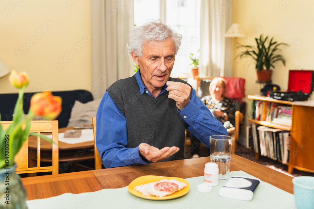 Focused senior man taking pills at home Focused senior man taking pills at home
