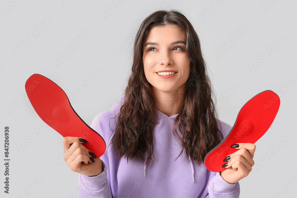 Young happy woman holding orthopedic insoles isolated on white background