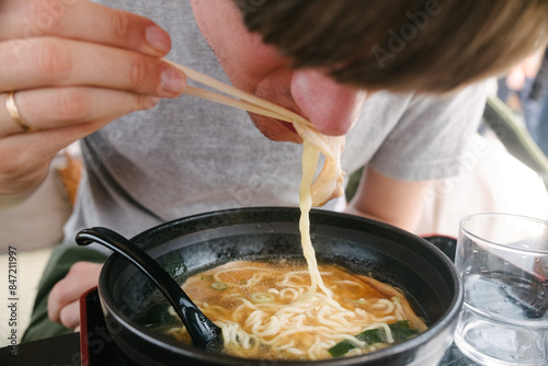 A man is eating noodles soup photo