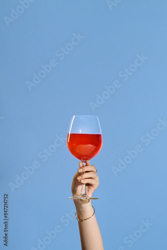 Woman holding a wine glass on blue background