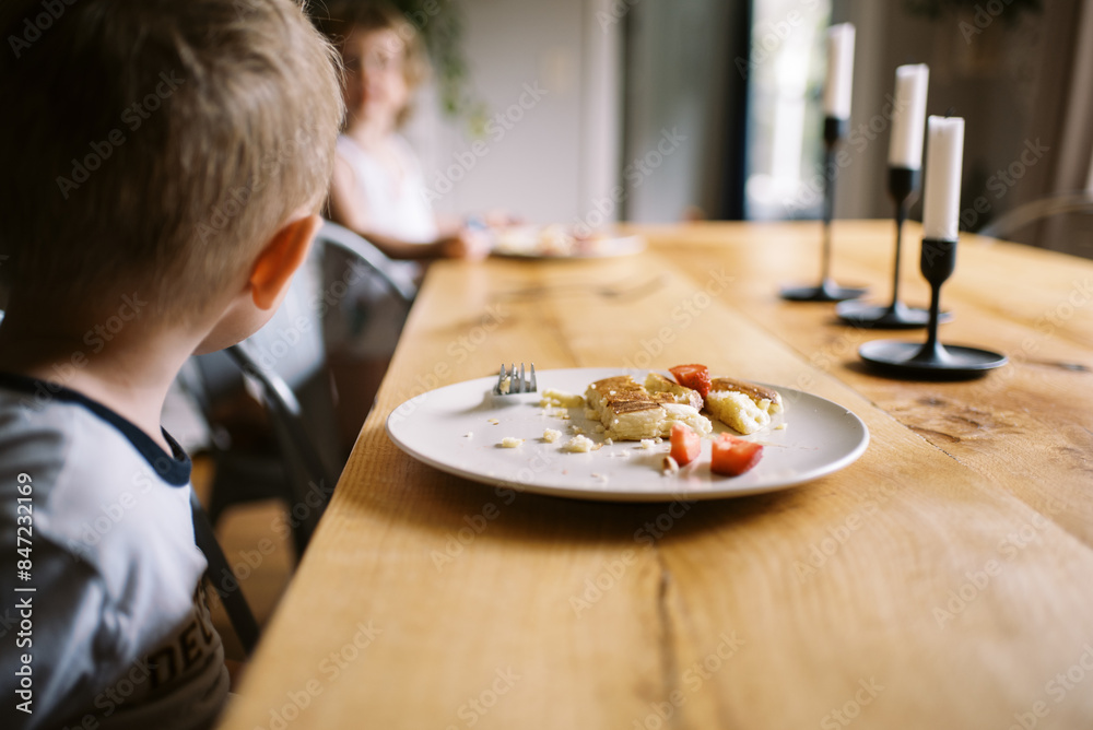 smiling boy eating breakfast pancake with strawberries smiling boy eating breakfast pancake with strawberries