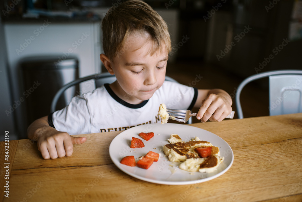 smiling boy eating breakfast pancake with strawberries smiling boy eating breakfast pancake with strawberries