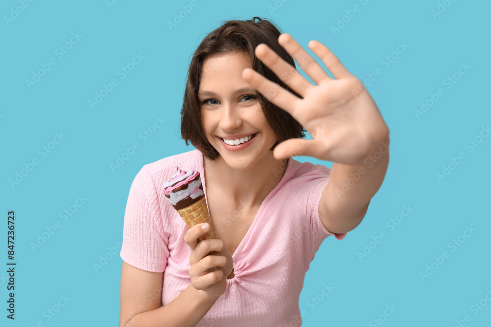 Happy young woman with sweet ice-cream in waffle cone on blue background Happy young woman with sweet ice-cream in waffle cone on blue background
