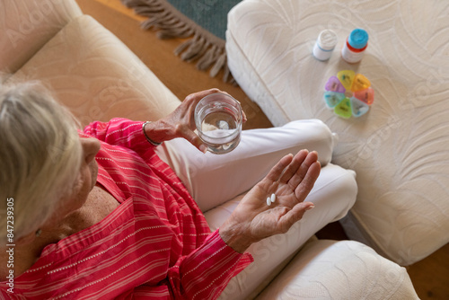 Senior woman holding prescription pill medication in hand at home