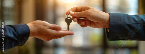 A real estate agent is handing over keys to a customer in an office  photo