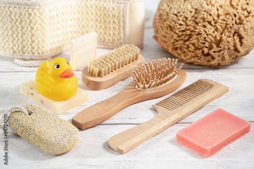 Bathhouse Sets on a White Wooden Background. Hairbrush, Natural Soap, Washcloth, Hair Comb, Toy Duck, Holystone as Various Eco Frendly Items from Bath for Face and Body Care photo