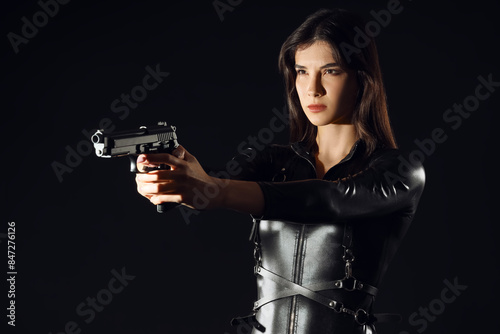 Female spy with gun on dark...