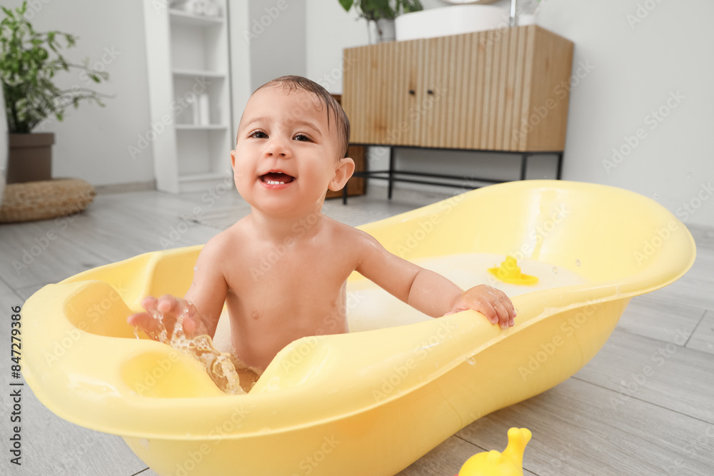 Adorable little baby washing in bathtub at home