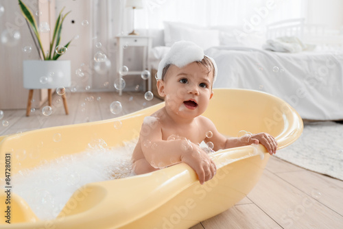 Fotografie Little baby bathing with foam and soap bubbles in bedroom