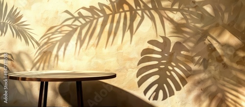 Shadow of monstera leaves on beige textured wall with table and mock-up for product presentation.
