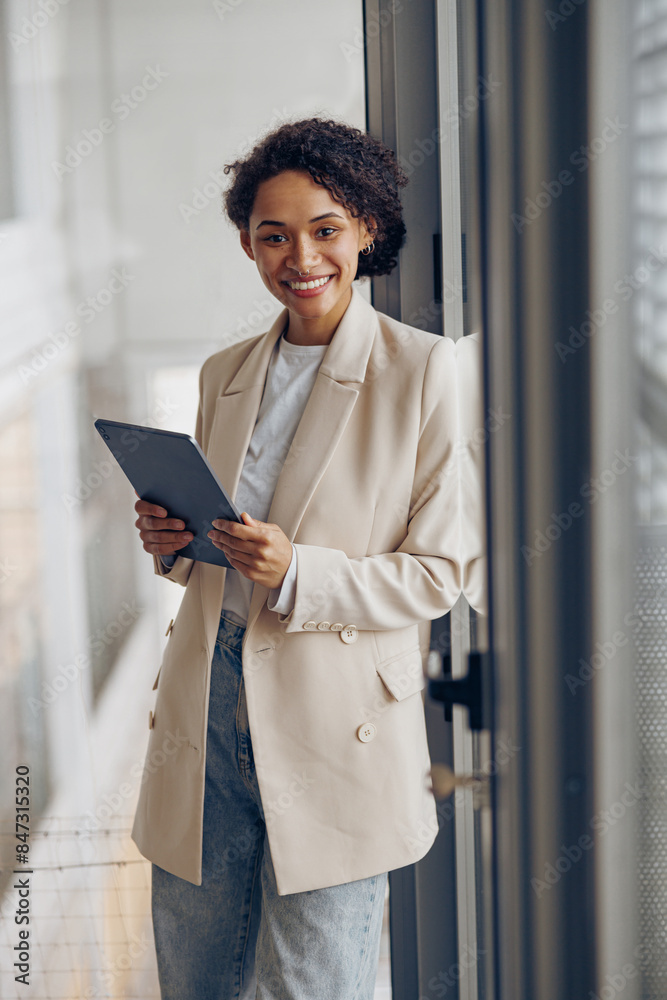 Female freelancer with digital tablet standing on modern coworking background and looks camera Female freelancer with digital tablet standing on modern coworking background and looks camera
