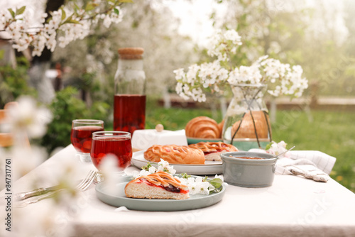 Fototapeta Naklejka Na Ścianę i Meble -  Stylish table setting with beautiful spring flowers, fruit drink and pie in garden
