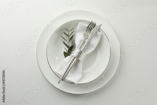 Stylish setting with cutlery and napkin on white textured table, top view