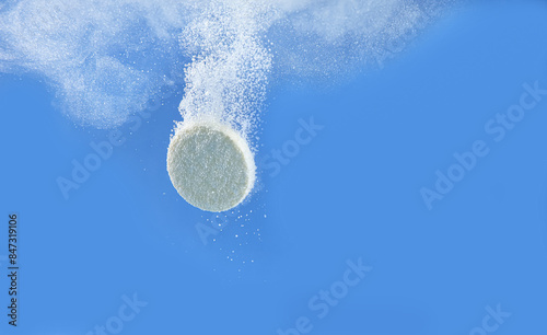 Картината върху платно Effervescent pill dissolving in water on blue background, closeup