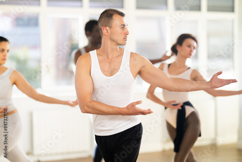 Concentrated women and men rehearsing ballet dance in studio