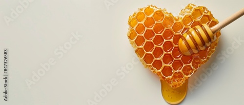 Heart-shaped honeycomb with honey dipper isolated on light background with copy space