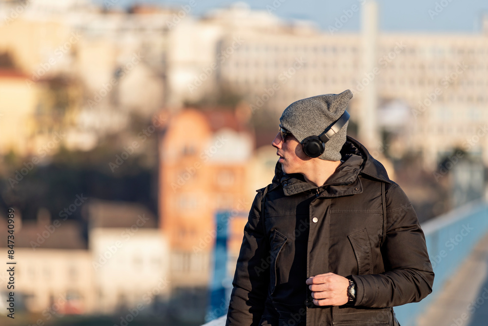 Young Man in the Winter City Streets with Headphones