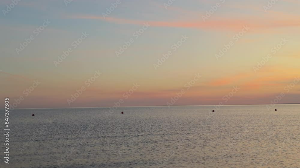 Peaceful scene on seaside. Pastel delicate colors sky with pink clouds above ocean with waves. Nature wallpaper with copy space. Background with sea water. Horizon. Quiet world. Round dots of buoys. Peaceful scene on seaside. Pastel delicate colors sky with pink clouds above ocean with waves. Nature wallpaper with copy space. Background with sea water. Horizon. Quiet world. Round dots of buoys.