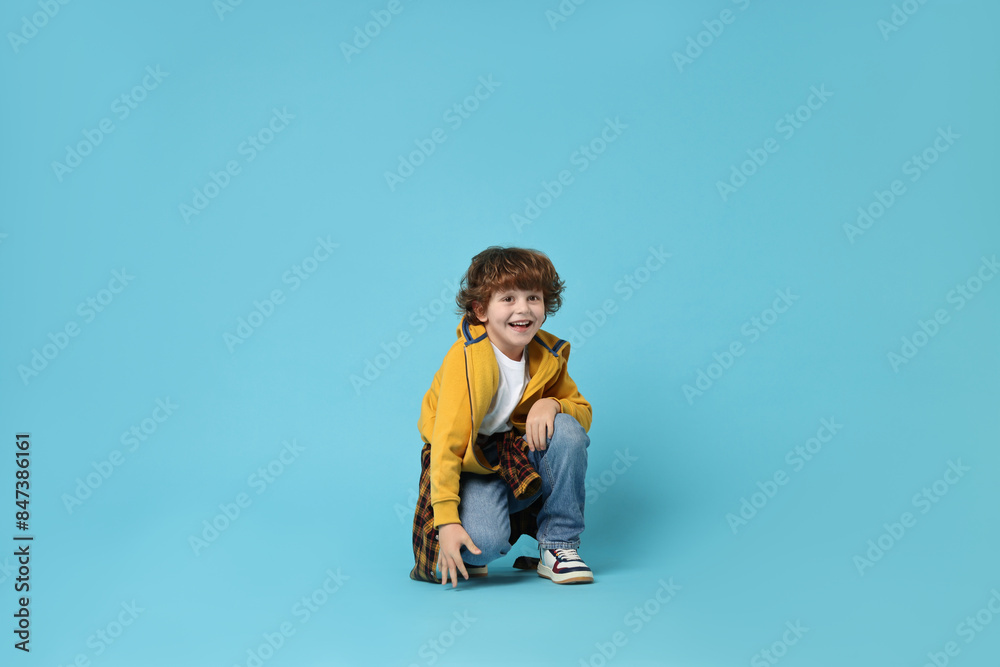 Happy little boy dancing on light blue background
