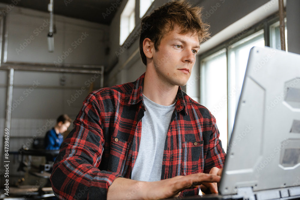A man uses a laptop working in the garage A man uses a laptop working in the garage
