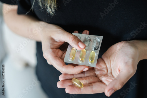Anonymous woman taking golden vitamin pills