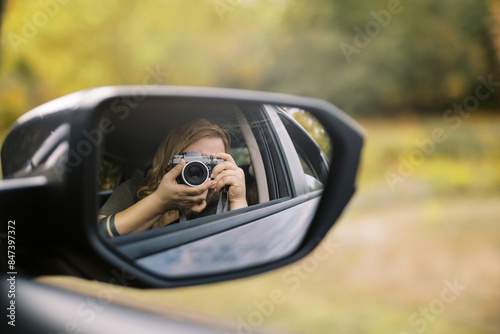 woman taking self portrait with camera in her car mirror