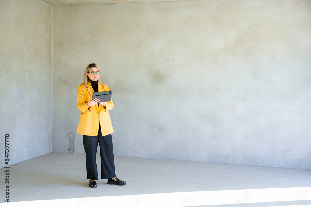 A real estate agent uses a tablet standing indoors A real estate agent uses a tablet standing indoors