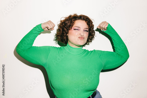 Confident curly-haired woman posing in green top